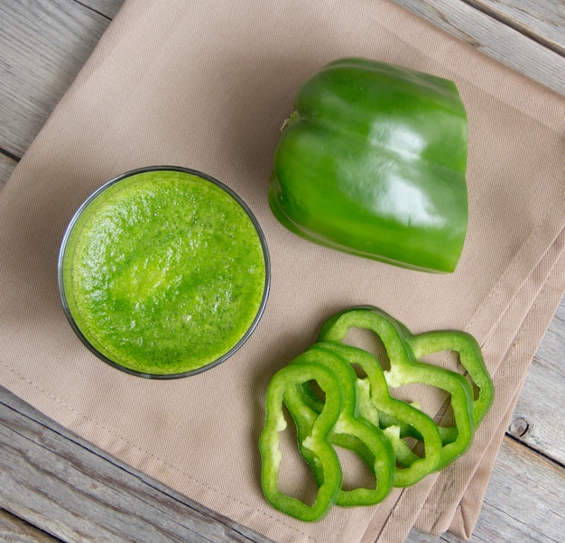 Smoothie vert frais à base de poivrons dans le verre sur une table en bois se bouchent