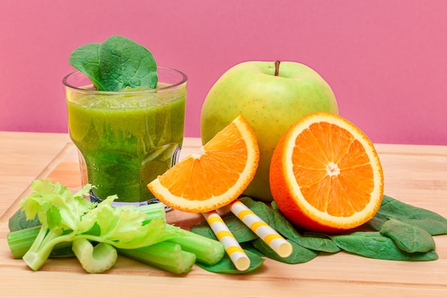 Smoothie vert frais d'épinards de céleri de pomme et d'orange dans le bécher en verre