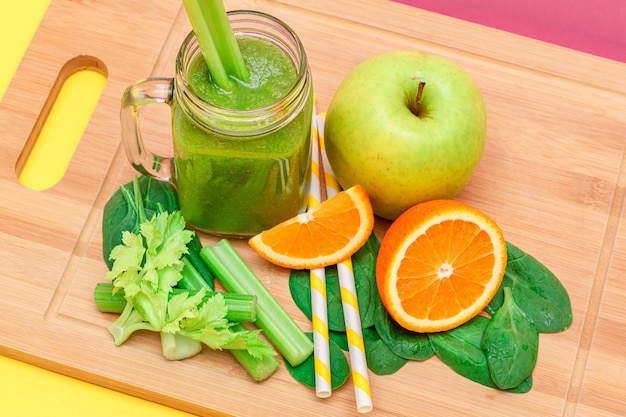 Smoothie vert frais de pomme, céleri, épinards et orange dans un pot de smoothie en verre