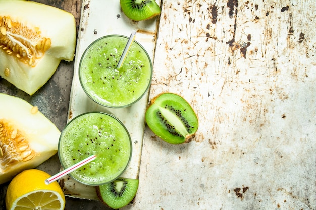 Photo smoothie vert de kiwi, melon et citron avec du miel. sur fond rustique.