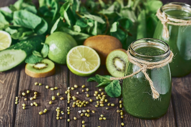 Smoothie vert mélangé avec des ingrédients sur la planche de pierre, mise au point sélective de table en bois