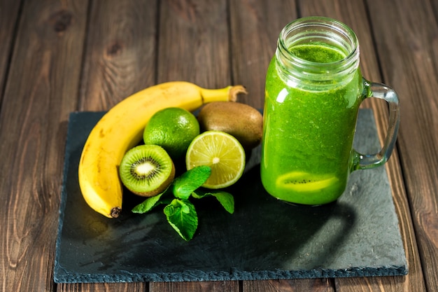 Smoothie vert mélangé avec des ingrédients sur la table en bois en pierre mise au point sélective