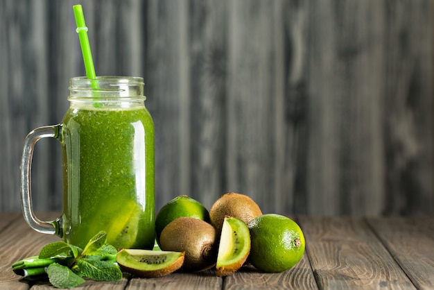 Smoothie vert mélangé avec des ingrédients sur la table en bois