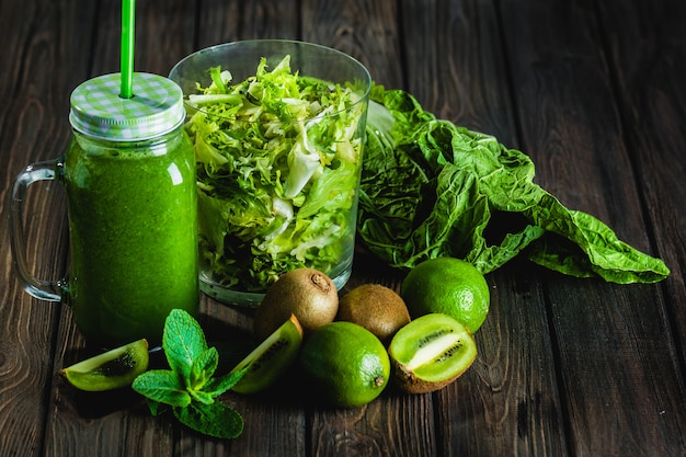 Smoothie vert mélangé avec des ingrédients sur la table en bois