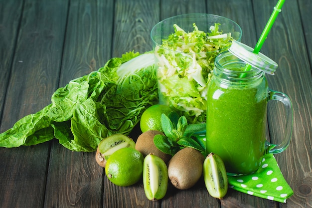 Smoothie vert mélangé avec des ingrédients sur une table en bois