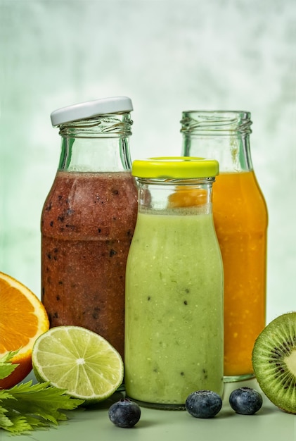 Smoothie vert orange et rouge dans des bouteilles en verre