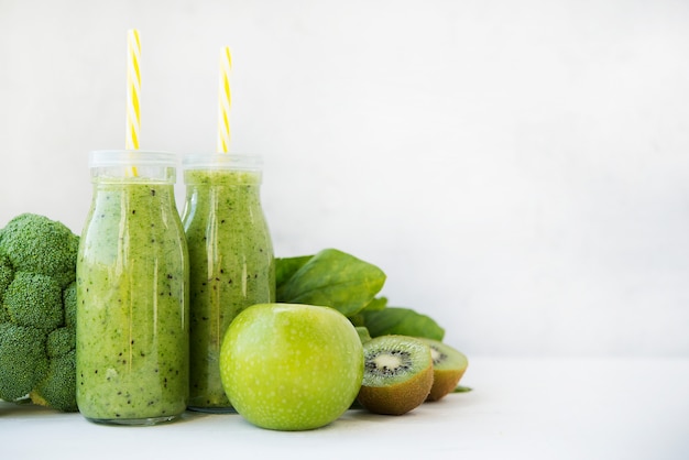 Smoothie vert végétarien avec légumes et fruits dans des bouteilles en verre, espace copie