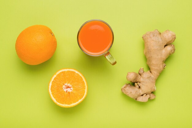 Smoothies au gingembre et à l'orange sur fond vert. Mise à plat.