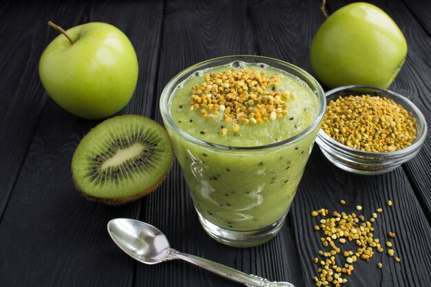 Smoothies au kiwi, pommes vertes et pollen d'abeille sur le fond en bois noir