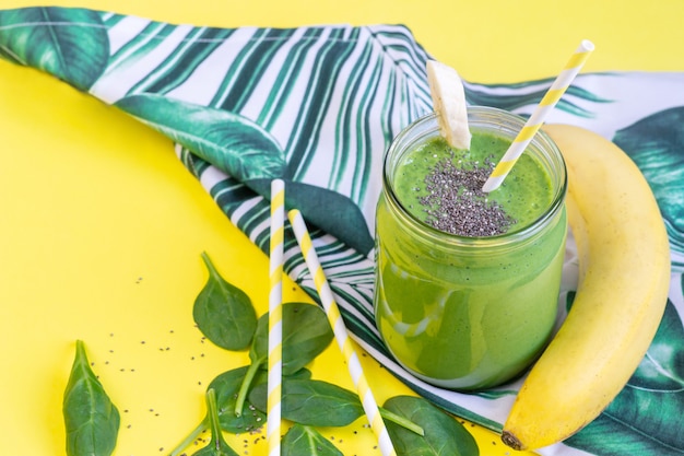 Smoothies aux épinards verts en pot avec des graines de chia, concept d'aliments sains, petit déjeuner, fond jaune