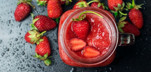 Smoothies aux fraises dans un verre transparent sur une table noire