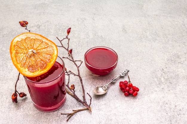 Smoothies et confitures biologiques frais naturels à base de viorne, de rose sauvage et de pamplemousse. Dans un verre sur une surface en pierre. Brindilles de rose de chien, pamplemousse séché