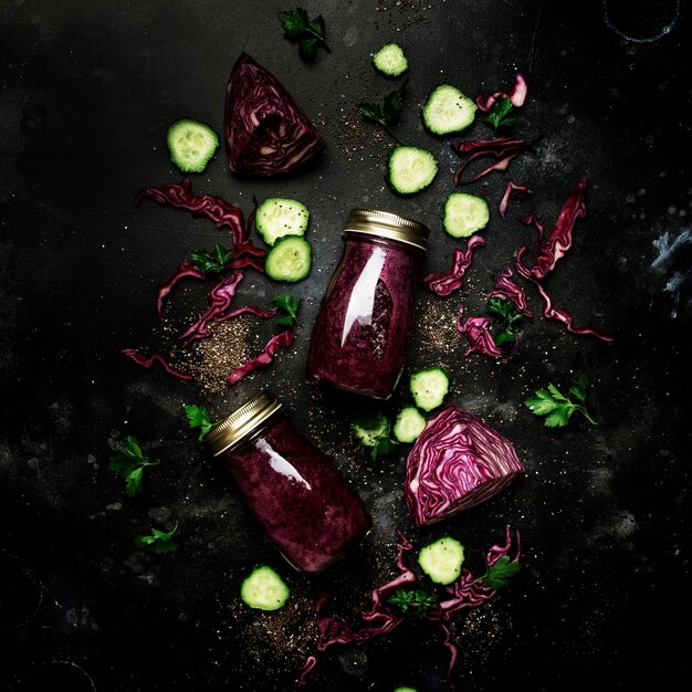 Smoothies détox sains ou jus de concombres de chou rouge avec des graines de chia dans des bouteilles en verre sur fond de table de cuisine grise concept de boisson de remise en forme végétalienne copie espace vue de dessus