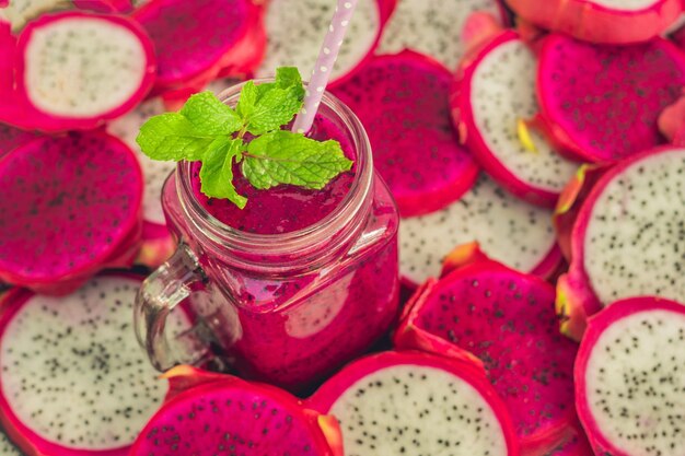 Smoothies de dragon fruit rouge biologique et des morceaux de dragon fruits sur un vieux fond en bois