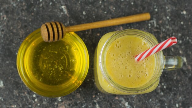 Smoothies fraîchement préparés avec mangue, banane, orange, miel et céréales sur une table en pierre noire