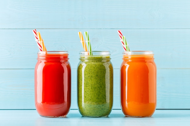 Smoothies / jus de couleur orange / vert / rouge dans un pot