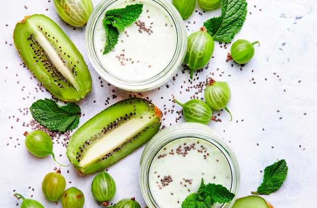 Smoothies et milkshakes à partir de cocktail de lait de groseille avec kiwi et yaourt graines de chia fond de table de cuisine gris plat vue de dessus