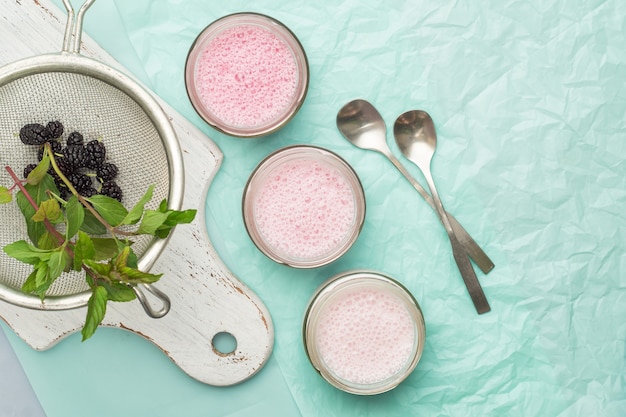 Smoothies de mûres et de menthe dans des bocaux en verre sur fond turquoise. Alimentation équilibrée