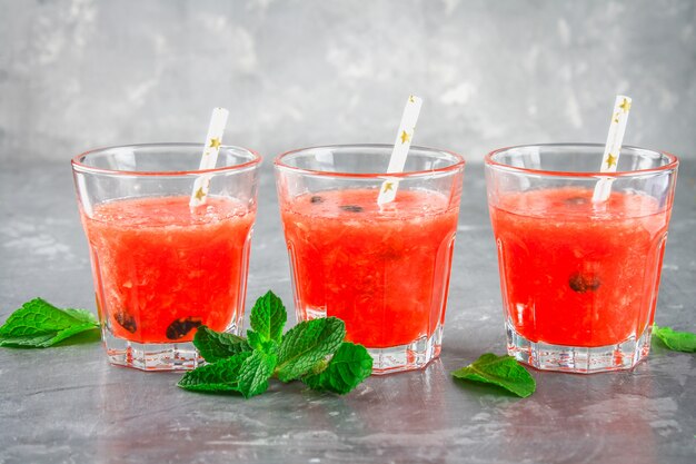 Smoothies à la pastèque dans des verres à la menthe laisse sur un fond de béton gris foncé.