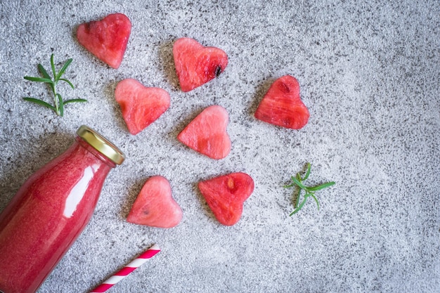 Smoothies pastèque romarin dans une bouteille Et morceaux de pastèque en forme de coeur