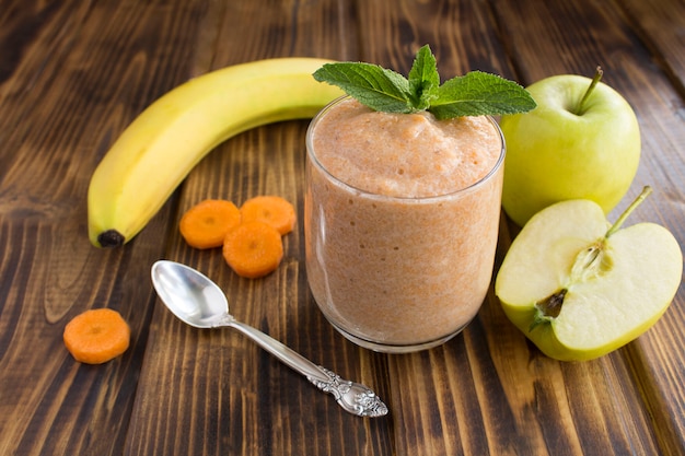 Smoothies ou purée à la banane, pomme et carotte sur le bois brun