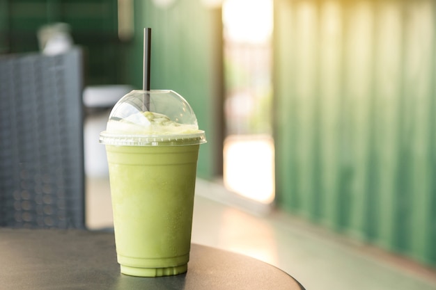 Smoothies de thé vert matcha dans une tasse en plastique dans le café