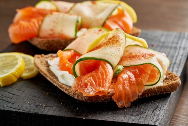 Smorrebrod - sandwichs danois traditionnels. Pain de seigle noir au saumon, fromage à la crème