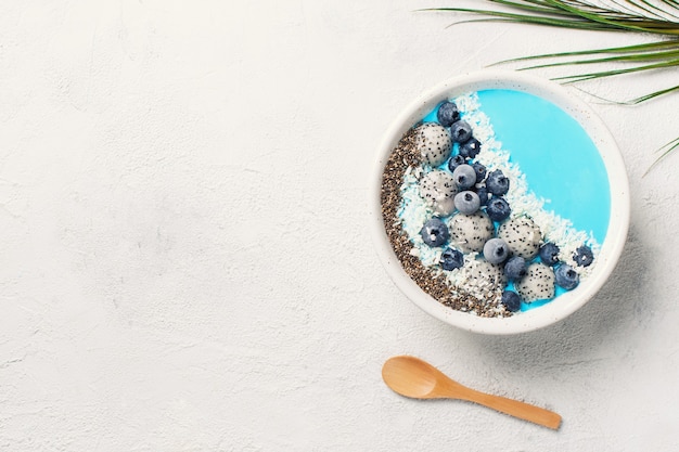 Smothie bleu dans un bol avec du granola et des baies