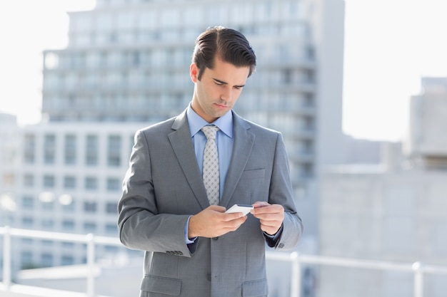 SMS d&#39;homme d&#39;affaires souriant avec son téléphone portable