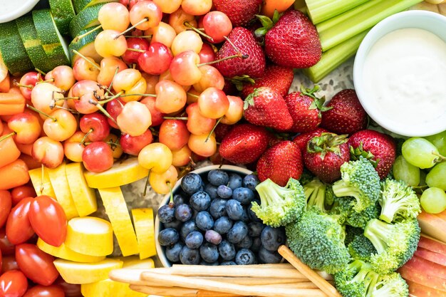 Snack board avec fruits frais, légumes, craquelins et trempettes.