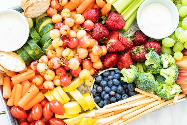 Snack board avec fruits frais, légumes, craquelins et trempettes.