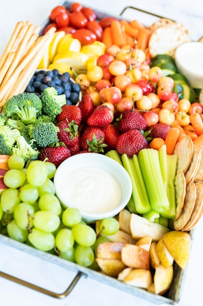 Snack board avec fruits frais, légumes, craquelins et trempettes.