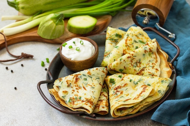 Snack ou déjeuner d'été Crêpes de courgettes aux herbes servies avec de la crème sure dans une assiette Espace de copie