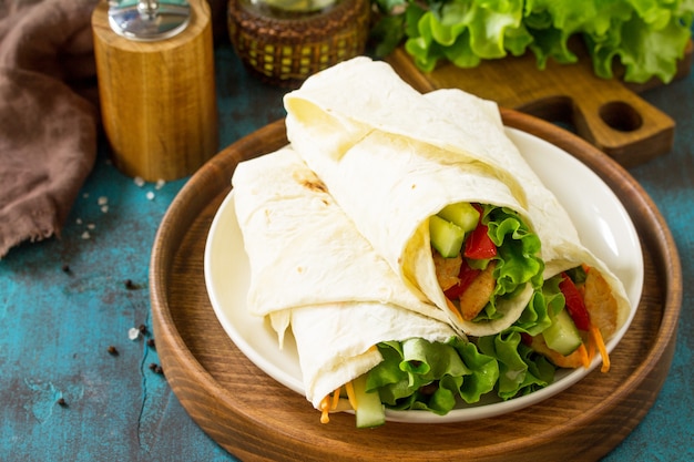 Snack déjeuner sain Tortilla wraps avec poulet grillé et légumes frais sur table bleue