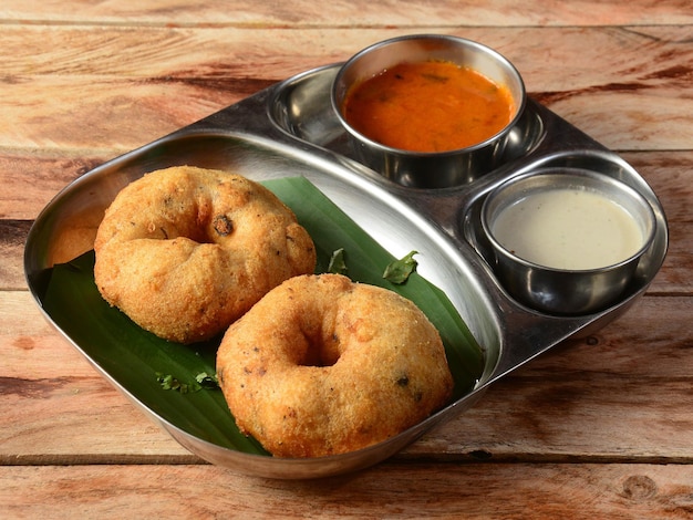 Snack frit indien Medu Vada avec sambar et chutney de noix de coco dans une assiette sur fond de bois rustique snack frit salé du Kerala Tamil Nadu et de l'Inde du Sud mise au point sélective