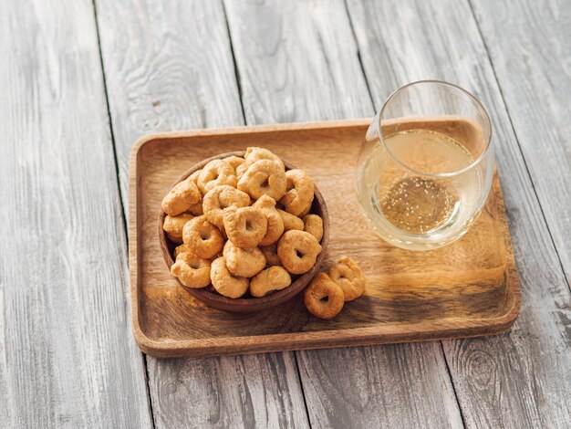 Photo snack italien traditionnel taralli ou tarallini dans un bol en bois et un verre à vin sur un plateau en bois sur un vieux fond en bois gris aperitif rustique de taralli avec espace de copie