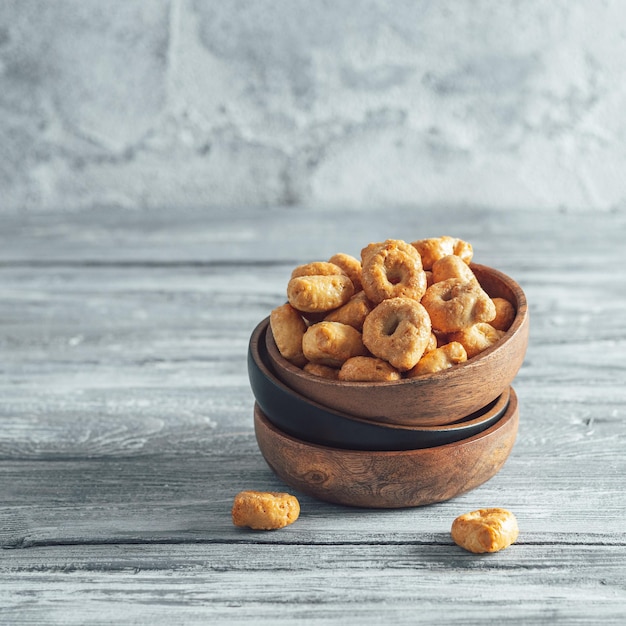 Photo snack italien traditionnel taralli ou tarallini dans un bol en bois sur une vieille table en bois grise aperitif rustique de taralli avec espace de copie crop carré