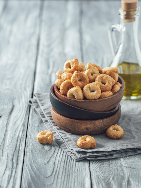 Photo snack italien traditionnel taralli ou tarallini dans un bol en bois sur une vieille table en bois grise aperitif rustique de taralli avec espace de copie vertical