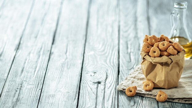 Photo snack italien traditionnel taralli ou tarallini dans un sac en papier sur une vieille table en bois grise aperitif rustique de taralli avec espace de copie bannière horizontale longue