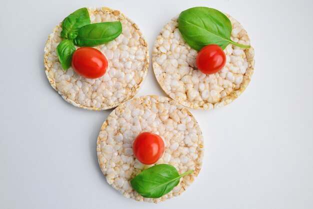 Snack De Riz Aux Tomates Cerises, Basilic Sur Fond Blanc. Collation Diététique. Vue De Dessus. Nutrition Adéquat.