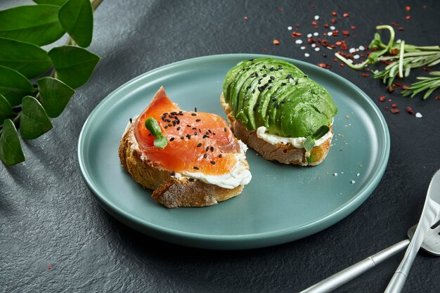 Snack de rue branché. Délicieux toasts au saumon et avocat sur du papier kraft sur une surface noire