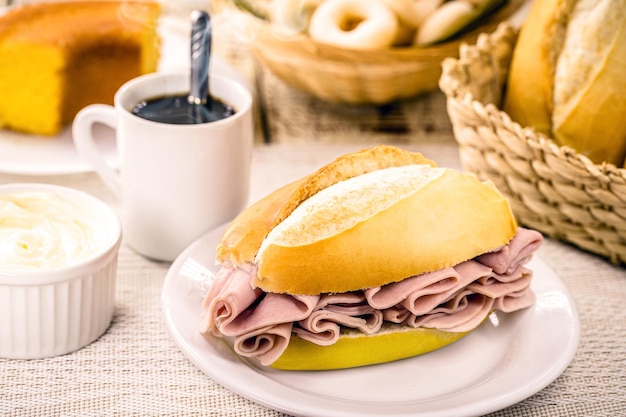 Snack typiquement brésilien pao de sal avec des tranches de fromage mozzarella et de jambon pain français pour le petit déjeuner avec du café chaud