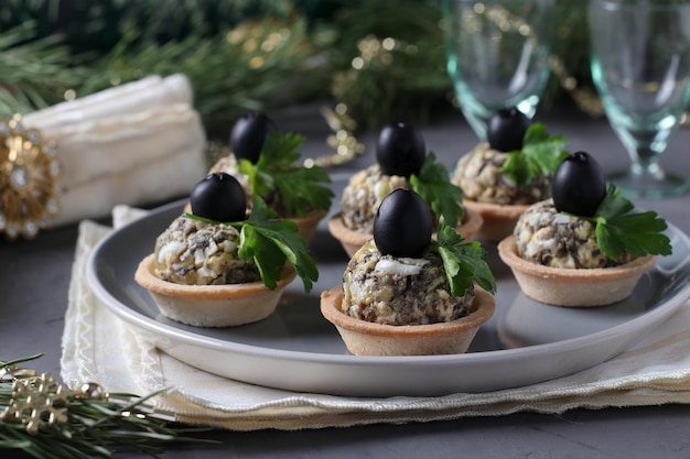 Snack de vacances en tartelettes aux champignons oeuf et olives noires sur fond gris