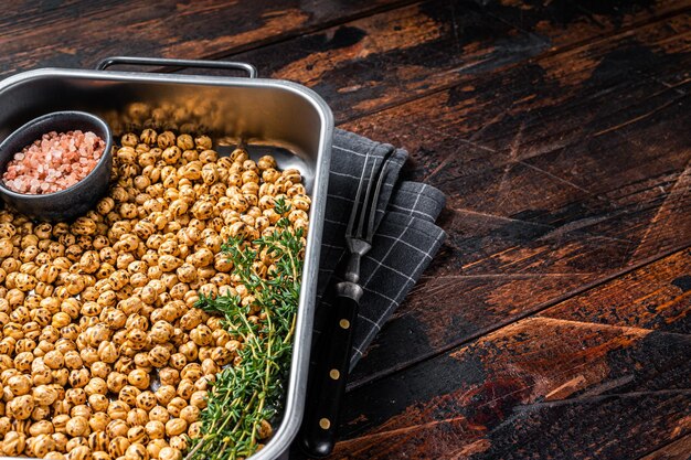 Snack végétarien de pois chiches épicés frits dans un plateau de cuisine. Fond en bois. Vue de dessus. Espace de copie.