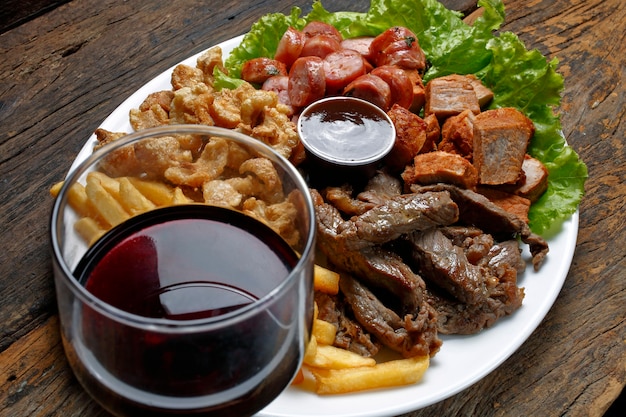 Snacks avec frites, craquelins, viande, porc, saucisse, sauce babercue et verre de vin rouge