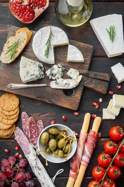 Snacks italiens, fromage à la viande, ensemble d'herbes, sur fond de bois foncé, vue de dessus