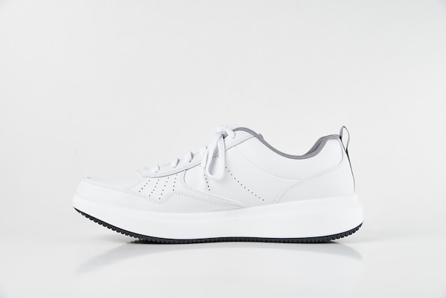 Sneaker mâle blanc sur fond blanc isolé. Chaussures de sport élégantes de mode, gros plan