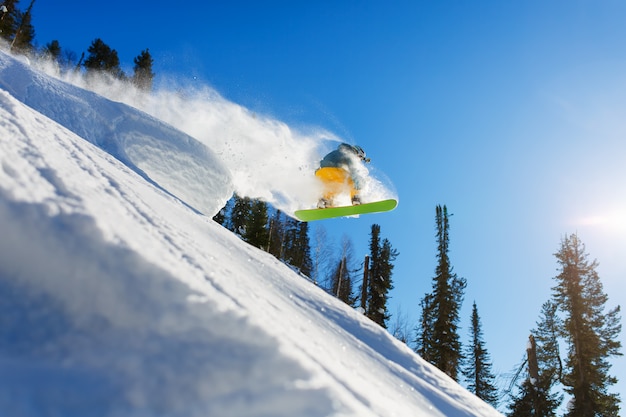 Photo snowboarder au saut dans les hautes montagnes à la journée ensoleillée.