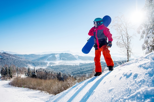 Snowboarder debout au sommet de la montagne à la recherche de repos après avoir roulé