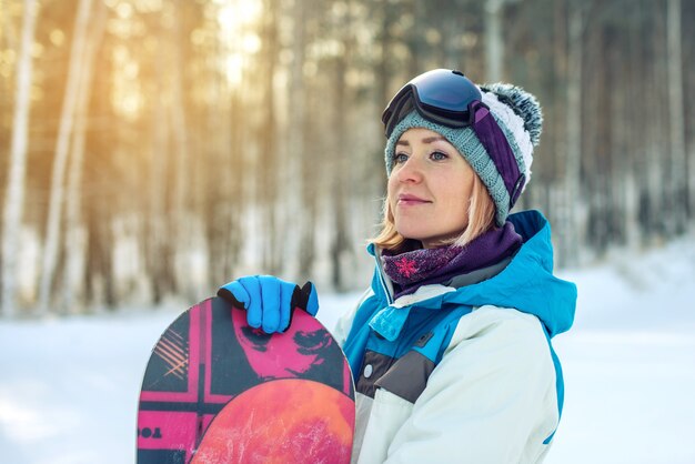 Snowboarder femelle avec snowboard parmi les arbres